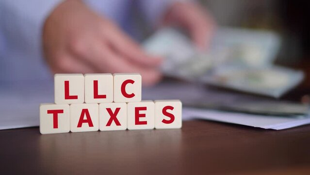 Concept of paying taxes for creating an Limited Liability Company. LLC taxes word with selective focus and person paying on the background.