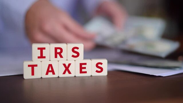 Concept of owing taxes to the Internal Revenue Service. IRS taxes word with selective focus and person paying on the background.
