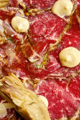 Close up Italian carpaccio with artichokes, arugula in a plate. A delicious snack