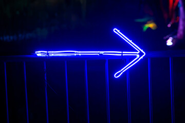 blue glowing led arrow in the night