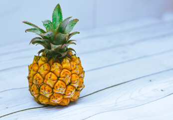 Exotic pineapple on a white wooden table, free space for text.