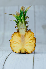 Half of sliced exotic pineapple on white wooden background