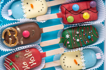 Christmas dessert. Sweet food. Cheesecake on a stick in the shape of ice cream. Children's treat in winter. Candy Christmas tree, snowman, deer and Santa Claus. Gingerbread cookies.