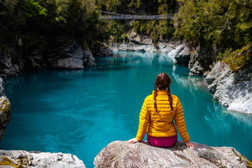 woman sitting on the rocks and enjoying unique blue water in hokitika gorge, west coast of new...
