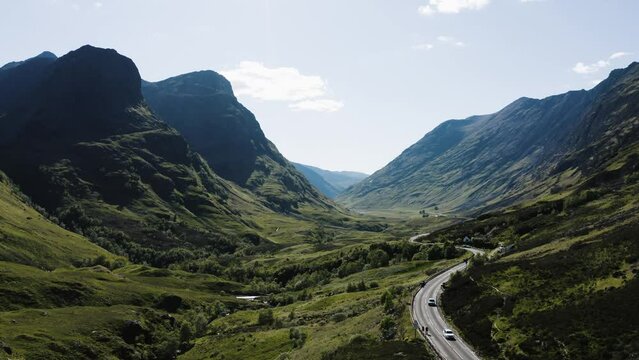 Drone shot of cars driving through the Glencoe Valley in Scotland.