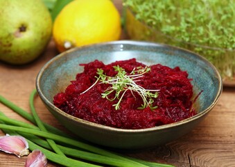 Traditional spicy beetroot salad with garlic and lemon juice. Bowl with beetroot salad decorated with garden cress.
