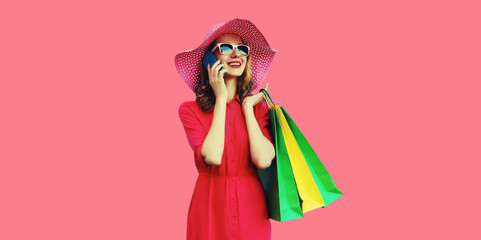 Beautiful happy young woman calling on mobile phone with shopping bag looking away in summer hat