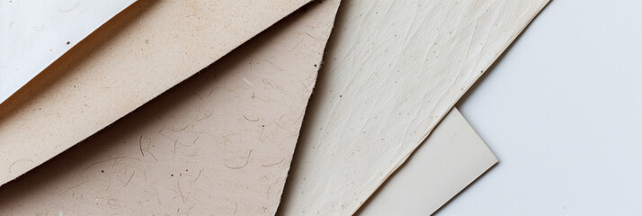 Various textured paper sheets in a neutral color palette, fanned out on a light surface, suitable for backgrounds or eco-friendly design concepts