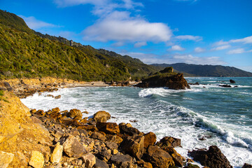 scenic west coast of new zealand south island; paradise beaches with large cliffs and little islands surrounded by rainforest covered mountains; paparoa national park near greymouth and westport