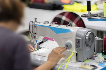 female dressmaker working on the factory using sewing machine close up shot