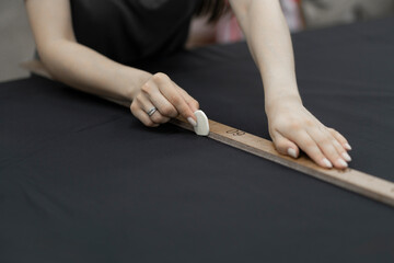 female tailor drawing a line with textile chalk in hand