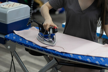 a clothing factory, seamstress ironing new wear in workshop