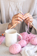 A woman knits and drinks coffee, winter hobby concept.