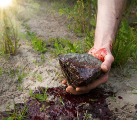 Bloodied hand with big stone
