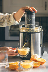 Woman preparing fresh orange juice for breakfast in kitchen.