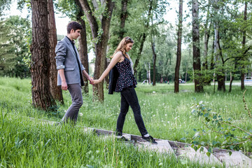 couple holding hands and walking in park on summer day, man holding woman hand