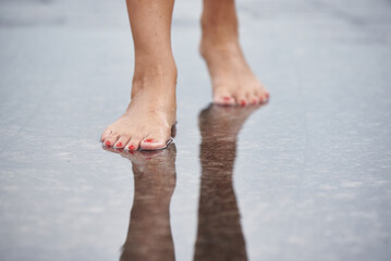 Women's feet walk through puddles.