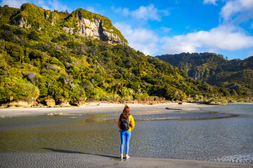 hiker girl enjoying a walk on the punakaiki beach, near pororari river lagoon, new zealand south...