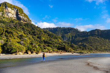 hiker girl enjoying a walk on the punakaiki beach, near pororari river lagoon, new zealand south island west coast