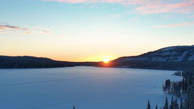 Sunrise Over Frozen And Snowy Lake Pyhajarvi In Tampere, Finnish Lapland, Finland. Aerial Pullback Shot