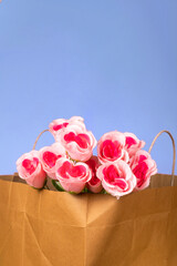 Bouquet of pink roses in a paper bag on blue background, valentine's day background