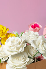 Bouquet of multicolored roses in a box on a pink background for Valentine's Day