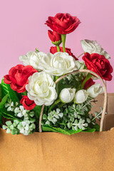 Bouquet of red and white roses in paper bag on pink background, close-up