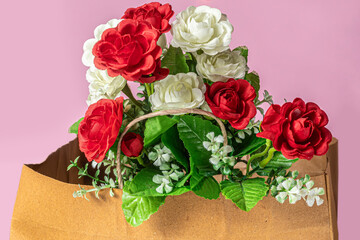Beautiful bouquet of red and white roses in a paper bag on a pink background