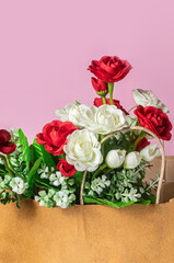 Bouquet of red and white roses in a paper bag on a pink background for Valentine's Day