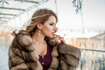 Portrait of beautiful woman wearing fur coat and red dress