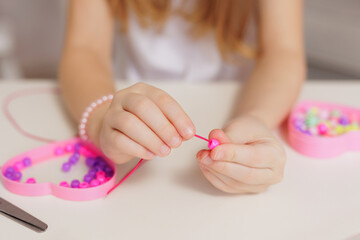 Close up of kids hands making beaded jewellery