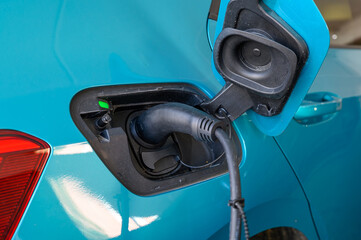Close up of power supply cable plugged into an electric car being charged. Close-up of plug while...