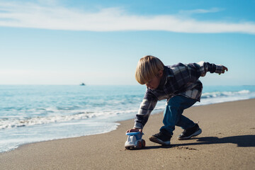 Toddler on vacation. Boy plays with a toy car on the seashore. boy 3-yers old playing on the...