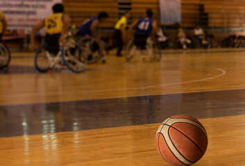 Athlete sitting in a wheelchair playing wheelchair basketball in a professional team. playing indoor basketball.