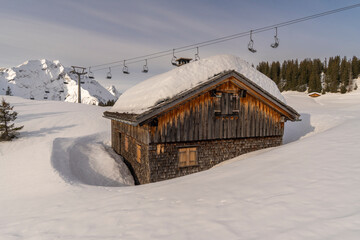 Panorama view with wooden holiday house on edge of forest in snowy mountains in Bregenzerwald,...
