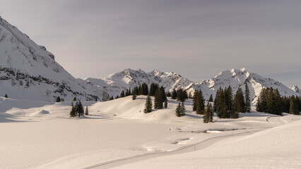 Panorama view with snowy mountains in Bregenzerwald, Austria, Körber lake with brown Arlberg peak...