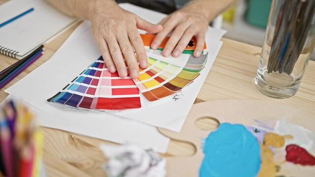 Man examining color swatches in a creative studio environment, suggesting design, art, or decoration planning.