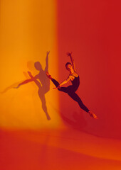 Fototapeta na wymiar Elegant Motion in Neon. Graceful dancer poses in black sports overalls, barefoot against gradient red-orange backdrop, her shadow adding depth to her movements. Concept of grace, athleticism, motion.