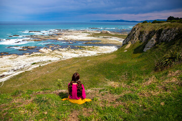 relaxed girl admiring the panorama of kaikoura peninsula from the top of a cliff; north canterbury,...