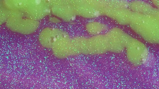 Lavender neon glitter paint and green drops pouring down the wall. Purple and neon green glitter paint or nail polish, sample texture.