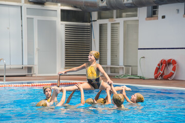 8 synchronized teenage girl doing tricks in the pool. Synchronized swimming, water sports. Amateur...