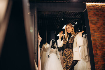 Lovely smiling young woman choosing evening dress in clothing shop
