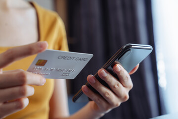 Girl holding credit card and using smartphone for shopping online with payment on internet banking.