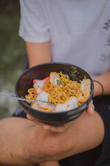 Person holding a bowl of noodle