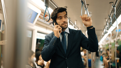 Smart business man phone calling to project manager while standing in train. Professional male...
