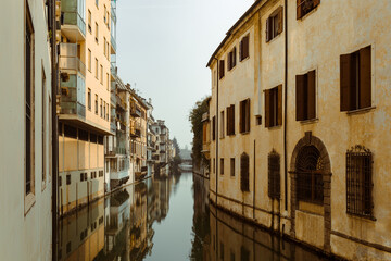 Fototapeta na wymiar The city canal San Massimo in Padua. Beautiful urban view of residential buildings with balconies in the center of the old city Padova, Veneto. Rivers Brenta and Bacchiglione, Italy