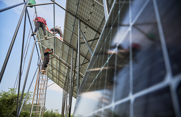 Workers installing solar panels on metal beams. Teamwork. Concept of renewable and ecological...