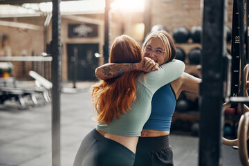 Women laughing and hugging after a workout at the gym