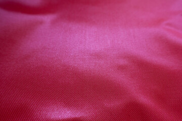 Closeup of vivid reddish pink satin polyester fabric