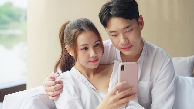 Asia people young adult man woman relax smile look camera take photo post to social media vlog video at outdoor hotel balcony enjoy date day. Happy asian lover wife husband just married sweet newlywed